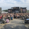 Large outdoor concert with stage and audience under a clear sky