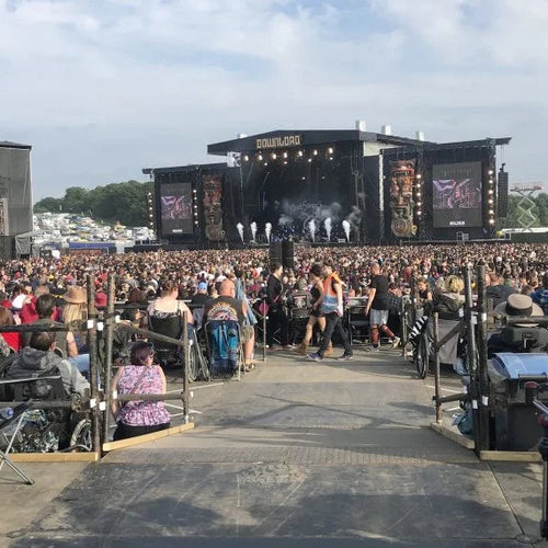 Large outdoor concert with stage and audience under a clear sky