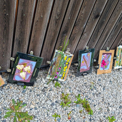 Small paintings on easels against a wooden fence