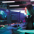 Person working at a computer with multiple monitors in a room.