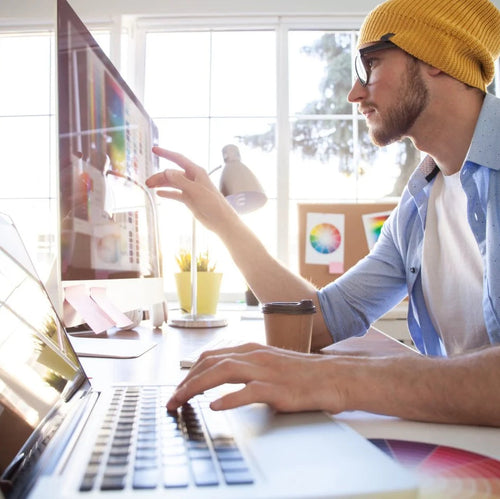 Person using a laptop with colorful graphics on a desk in a bright room.