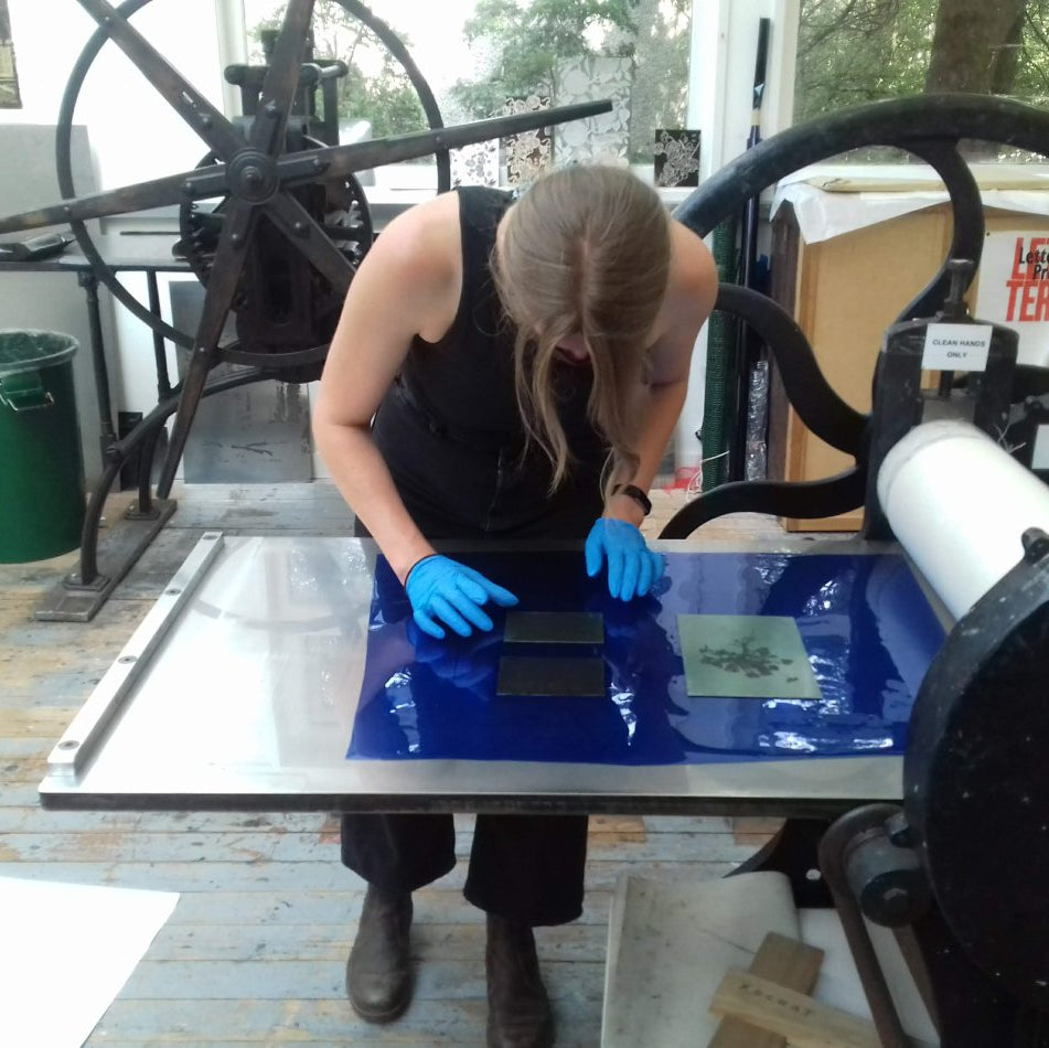 Person working with a screen printing press in a workshop setting