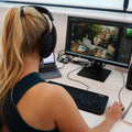 Person wearing headphones working on a computer with dual monitors at a desk.