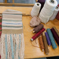 Woven fabric and spools of yarn on a wooden table